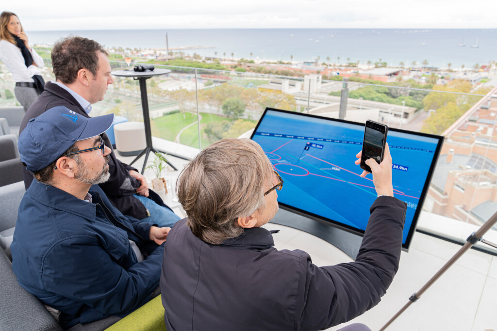 Invitados siguiendo la regata en una pantalla táctil con el recorrido en directo durante el encuentro de NTT DATA