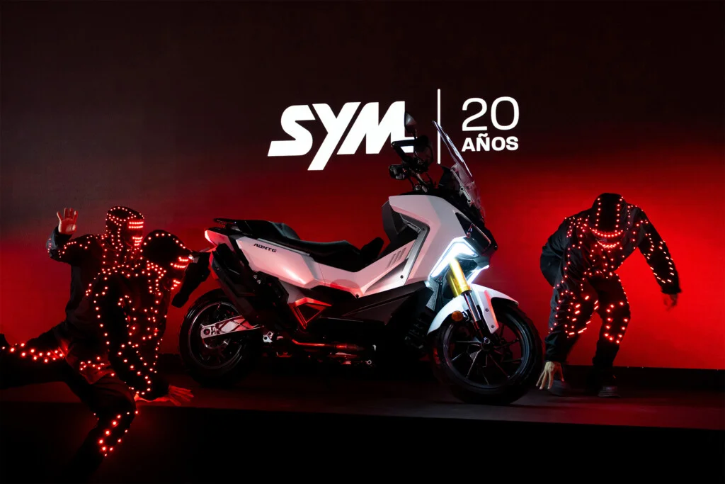 Unveiling of a SYM scooter, with dancers in LED light suits in front of the SYM 20 years logo, at the SYM España anniversary