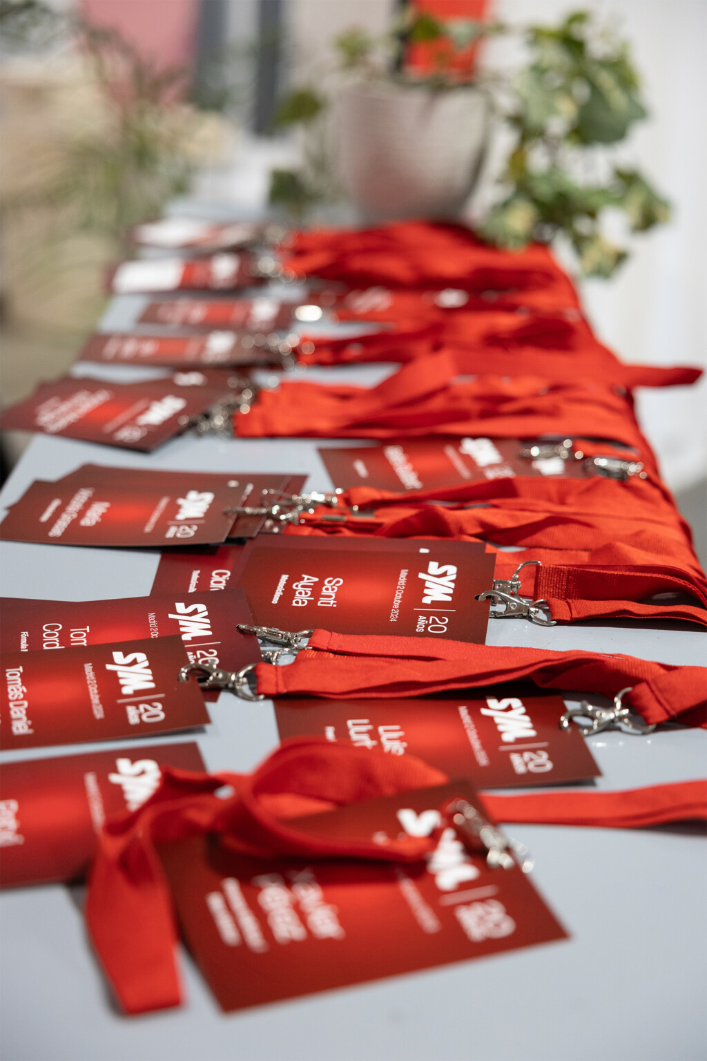 Passes and red lanyards for SYM España’s 20th anniversary on the reception desk