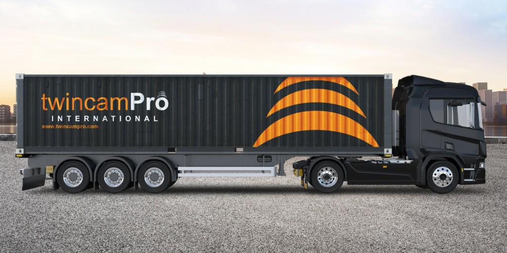 Recreación: camión con contenedor negro rotulado con el logotipo de TwincamPro International y los arcos del símbolo en naranja