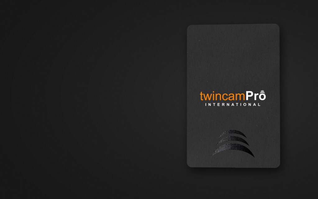 Reverso negro de la tarjeta de TwincamPro International con el logotipo en naranja y blanco y el símbolo de tres arcos en barniz